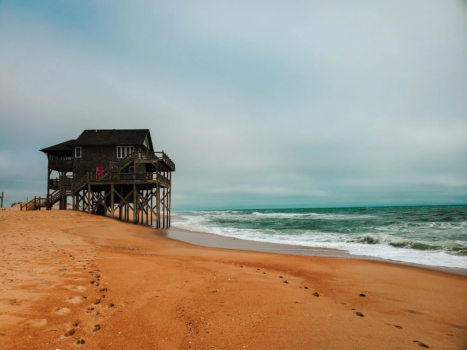 A weathered cedar-shake house on wooden pilings standing in the surf at Rodanthe, North Carolina